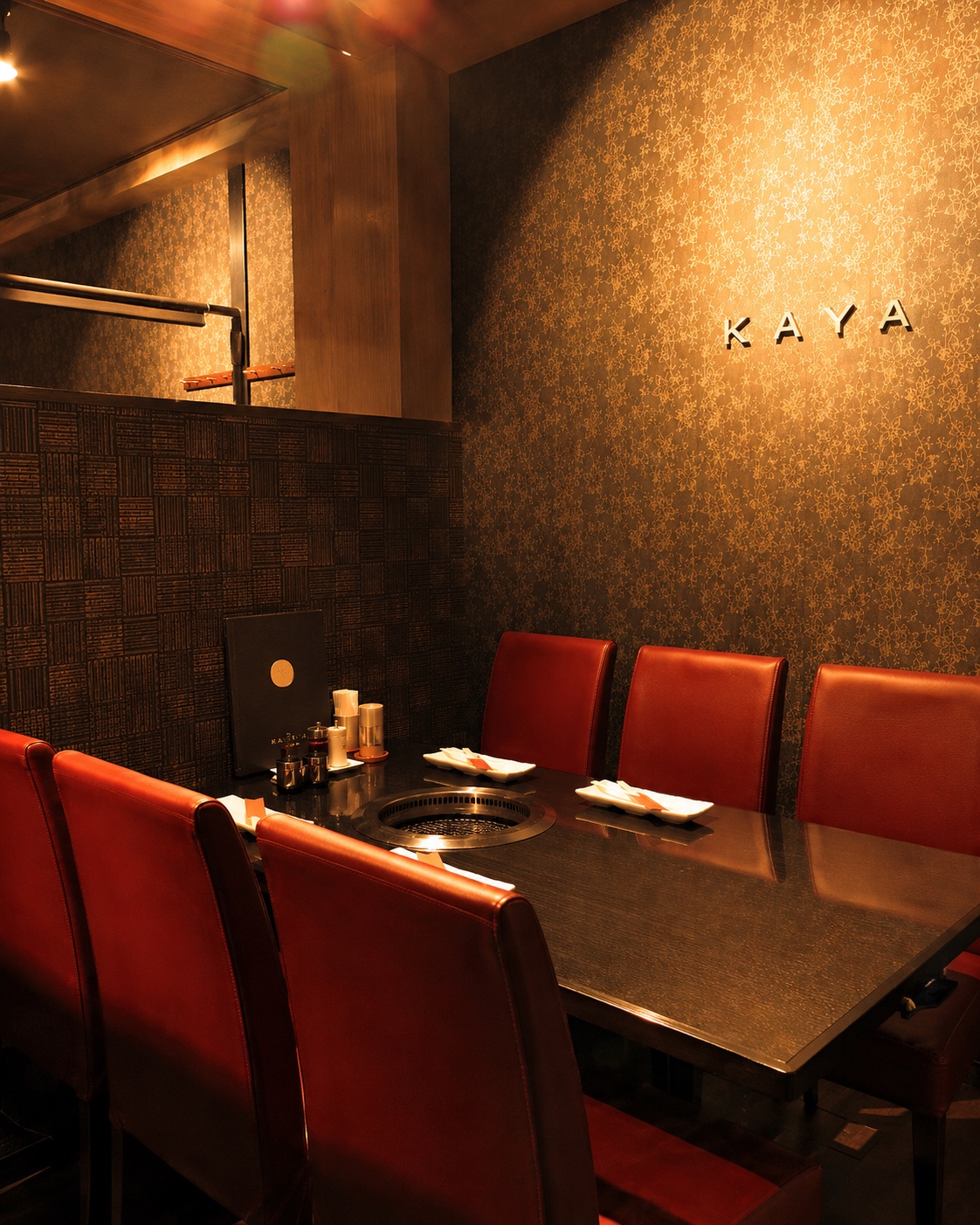 KAYAのロゴと深い赤の座席が印象的な店内